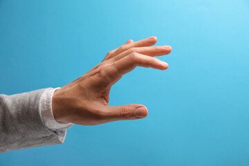 Wall Mural - man holding something in hand on light blue background, closeup. space for text