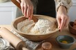Woman kneading dough with spoon in bowl at wooden table indoors, closeup