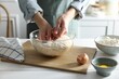 Woman making dough at white wooden table in kitchen, closeup