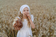Close-up of rye bread in the hands of a blonde girl in a field of rye