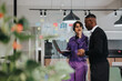 © qunica.com - Focused Indian woman in a business meeting with a male colleague. They are discussing project details in a brightly lit office setting with visible glass writing board.