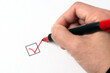 Close-up photo of a big red tip marker pen writing a tick on white paper