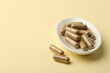 Vitamin capsules on pale yellow background, space for text