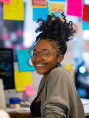 Wall Mural - Smiling african american girl at her workplace, working hard in the office at her desk. Pleasant working atmosphere