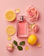  A pink perfume bottle with roses and lemons on pastel pink background. Minimal beauty concept.