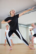 Mature active woman dancing during group training practices energetic swing
