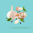 Garlic clove with parsley leaves and pepper
falling on tranquil background.