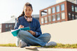 Young Girl Sitting on Ground With Book and Headphones