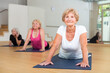 Three mature women practicing yoga in a group class perform an exercise in the dog pose face up