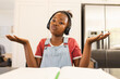 An African American girl wearing headphones, shrugging during video call at home
