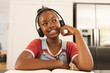 An African American girl wearing headphones, smiling during video call at home