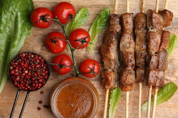 Wall Mural - Tasty cooked marinated meat served with sauce and tomatoes on wooden table, flat lay