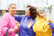 Three happy cheerful pensioner female friends in bright sweaters and sunglasses walk together