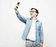 Portrait of a young handsome man taking a selfie, holding a phone