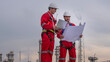 Engineer wear uniform and helmet stand workplace hand holding tablet computer, survey inspection team work see detail blue print plant site to work with oil refinery  background.