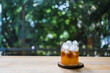 Orange juice with black coffee and mini round ice cubes in glass on wood table, homemade drink