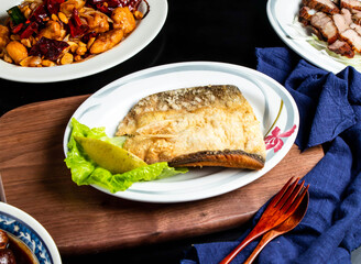 Pan fried fish maw with lemon, spoon and fork served in dish isolated on wooden board side view of taiwan food