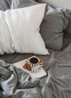 Cozy morning. A lazy morning - black coffee, cookies, magazine in bed with grey linen bedding, top view