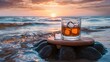 Whiskey with ice on rocks near the sea at sunset