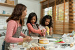 © Kawee - Asian attractive mother making cake with daughters in kitchen at house.