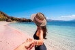 Young couple tourism enjoying the tropical pink sandy beach with clear turquoise water at Komodo islands in Indonesia