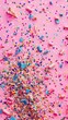 Colorful sprinkles and confetti on a pink background