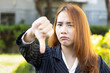 Angry upset Asian office worker woman shows rejecting thumb down gesture, concept image for bad job, rejection, not pass, failure, failed deal, bust, poor performance, position demotion