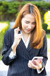 Excited Asian office worker woman showing wishing with finger crossed gesture while looking at smartphone