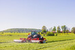 Tractor harvesting grass on a field in a rural landscape view