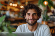 Happy young man with laptop in a cozy cafe setting