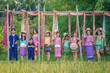 Agriculture organic rice field farm for health. Happy Asian Thai group of boys and girls wear traditional colorful farmer outfits walking on a beautiful green rice field in Thailand.