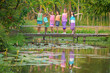 Happy Asian Thai group of boys and girls wear traditional colorful farmer outfits walking on a beautiful green rice field in the countryside Thailand.