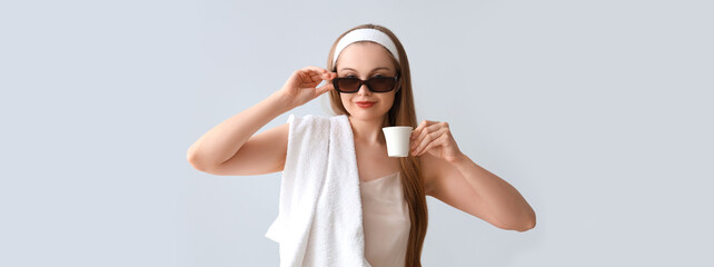 Poster - Pretty young woman in pajamas, with towel and coffee on light background