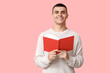 © Pixel-Shot - Handsome young man reading book on pink background
