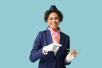 Sticker - Beautiful African-American stewardess with toy plane on blue background