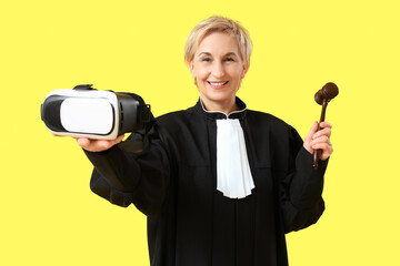 Canvas Print - Mature female judge with VR glasses and gavel on yellow background