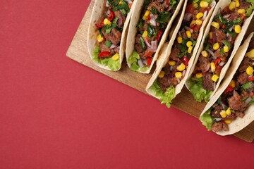 Wall Mural - Delicious tacos with meat and vegetables on red table, top view. Space for text