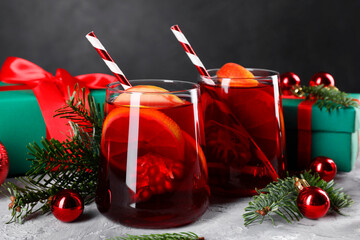 Wall Mural - Delicious Sangria drink in glasses and Christmas decorations on grey textured table, closeup