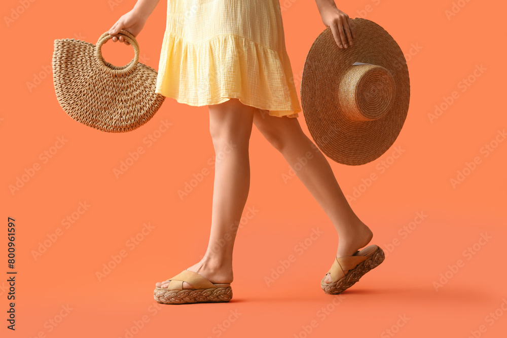Young woman with straw bag and hat on orange background
