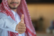 A Saudi Arabian man in traditional dress giving a thumbs up.