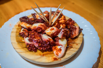 Cooked octopus Tentacles Served on a Wooden Plate in a Cozy Restaurant Setting, Pulpo a la Gallega, Spanish Tapa