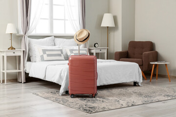 Poster - Suitcase with hat in interior of light hotel room