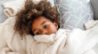 Pensive sad african american child girl lying on pillow in bed at home. Sick ill virus child concept