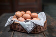 Chicken eggs in a lined basket on an old rustic wooden table. Natural healthy food in a vintage setting still life