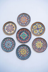 Wall Mural - traditional Uzbek ceramic plates hand-painted on white wall at the oriental souvenir tableware shop in Uzbekistan