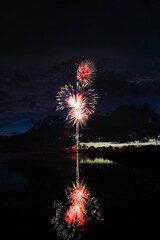 Poster - a firework in the sky at night over water and hills