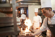 © peopleimages.com - Cooking, chef and team in kitchen with fire on frying pan at restaurant for fine dining, service and training. Expert, culinary professional and group of people preparing dinner for food catering