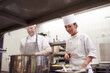 © peopleimages.com - Cooking, chef and trainee in kitchen with pot for food preparation, fine dinning and gourmet cuisine. Professional cook, people and catering in restaurant with ingredients for luxury meal or lunch