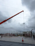 Fototapeta Uliczki - Assembling Holiday Cheer: Crane at Work by the Harbor