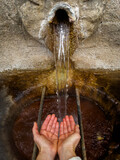 Fototapeta Uliczki - Catching Water from an Ancient Stone Fountain